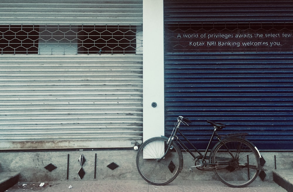 blue city bicycle parked beside white roll up door