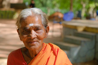 An elderly woman practicing slow tai chi movements in a sunlit garden surrounded by soft teal and warm cream tones.