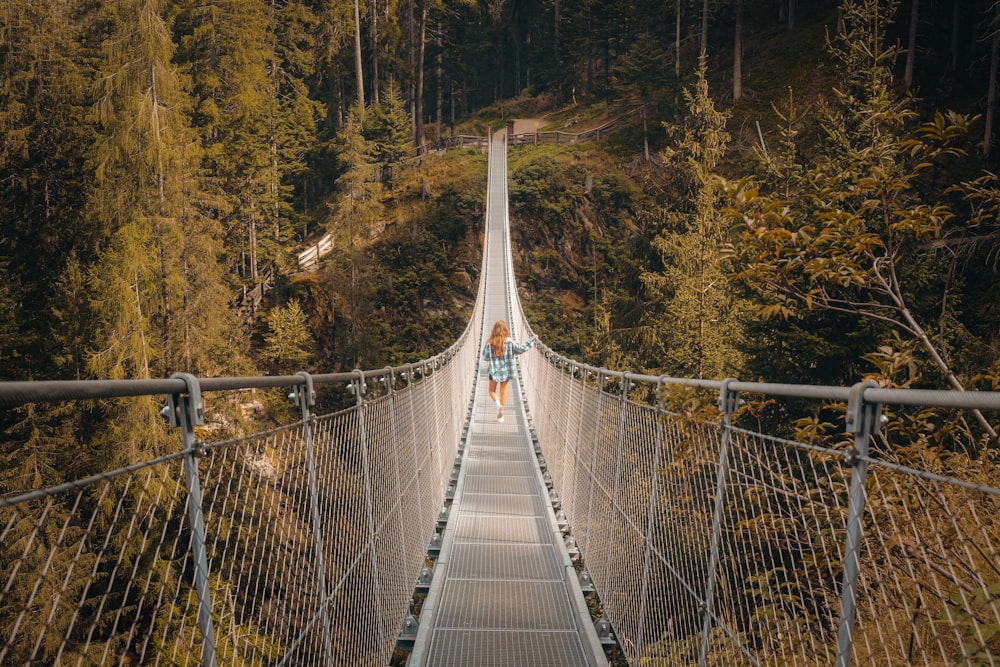 white and brown hanging bridge surrounded by green trees during daytime