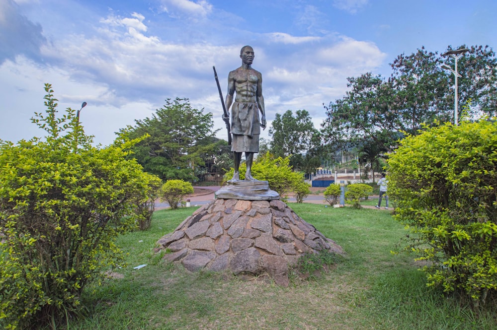 brown concrete statue near green trees under blue sky during daytime