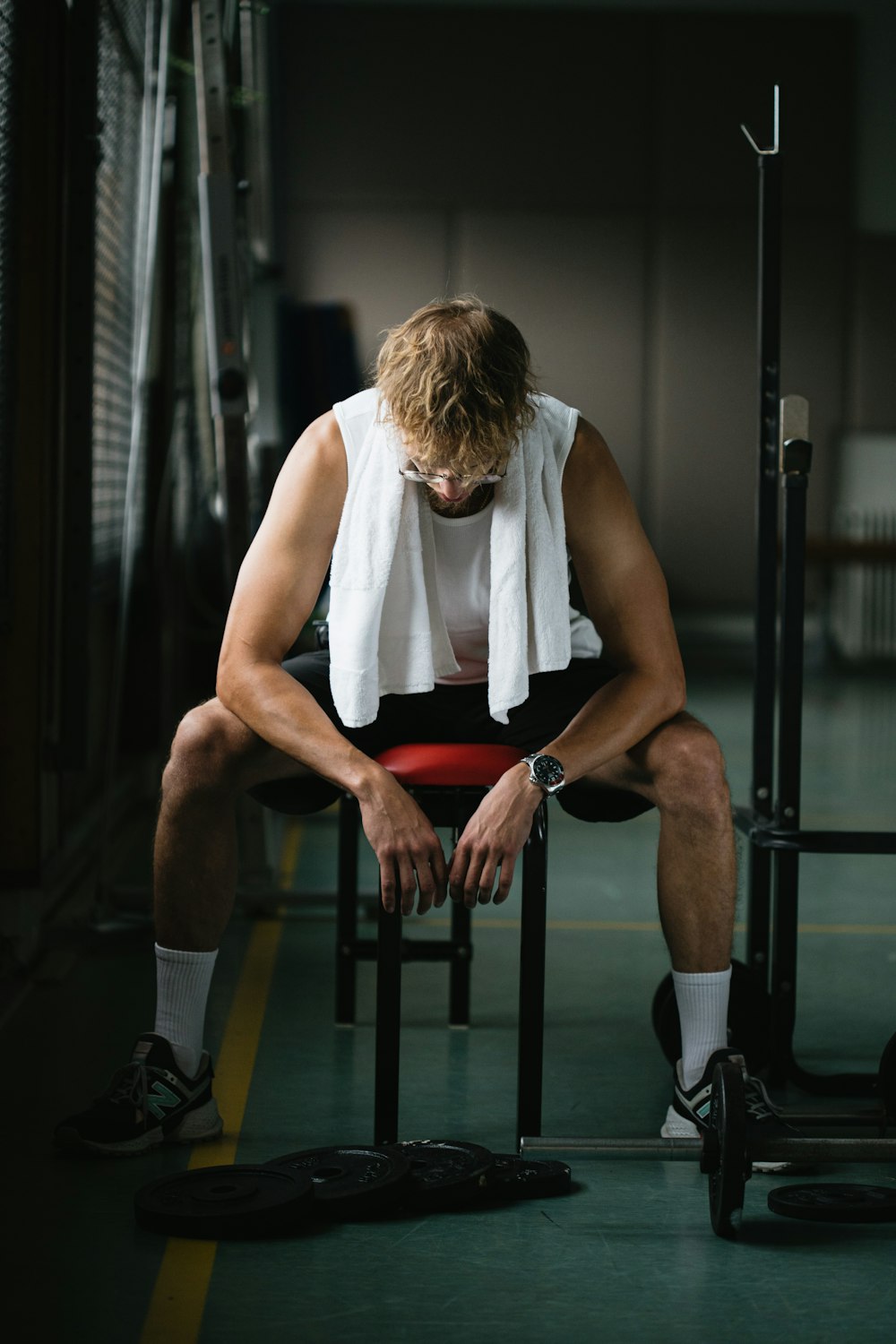 woman in white sleeveless shirt and red shorts sitting on black exercise bench