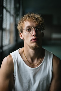 portrait photography,how to photograph fitness, but make it fashion and add a story  background: shot in my high school's gymnasium, my sister's boyfriend, all natural light, used two lenses (50mm and 100mm); man in white tank top wearing black framed eyeglasses