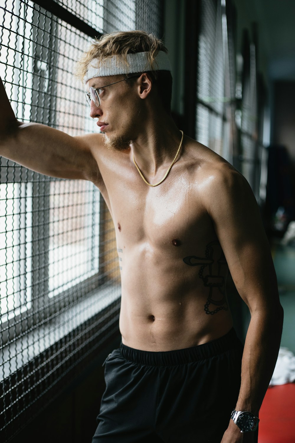 topless man in black shorts standing beside black metal fence during daytime