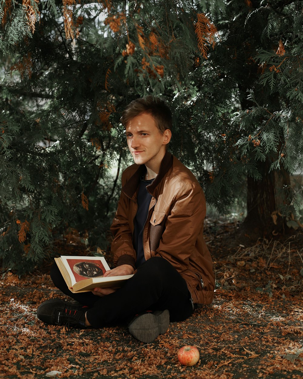 woman in brown leather jacket sitting on ground with white book