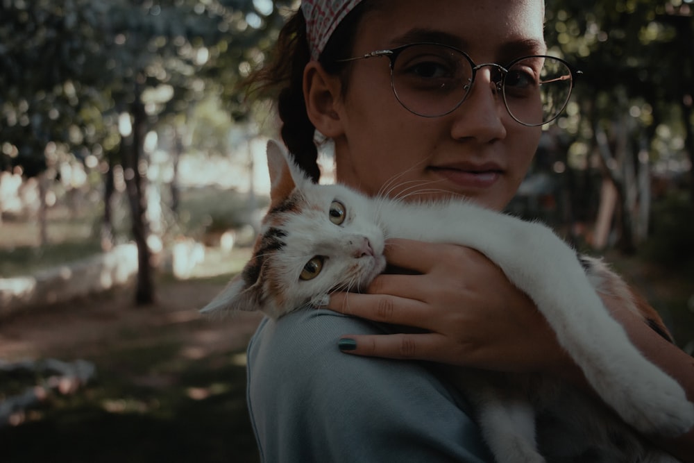 Femme en pull bleu tenant un chat blanc