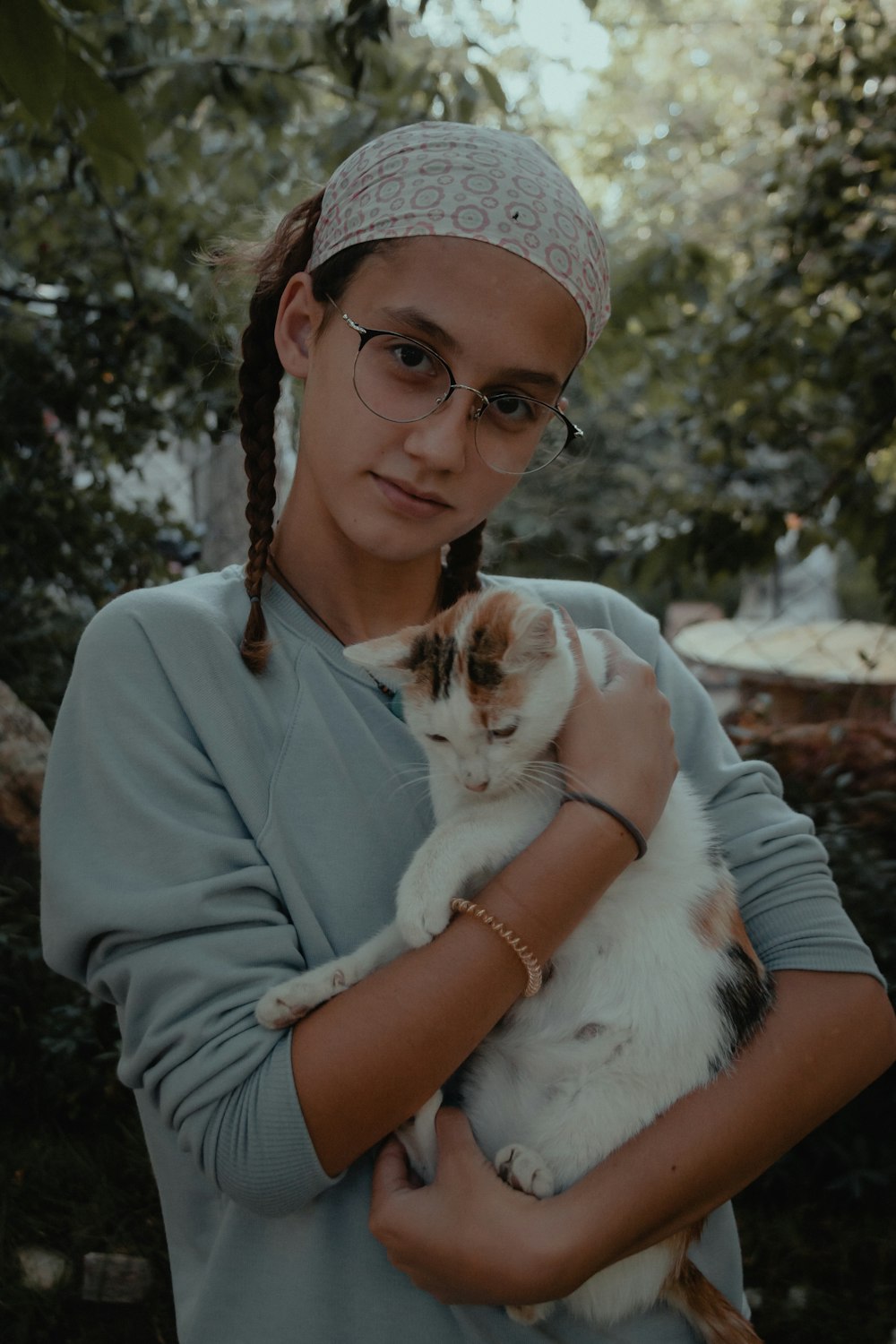 woman in gray long sleeve shirt holding white and brown cat