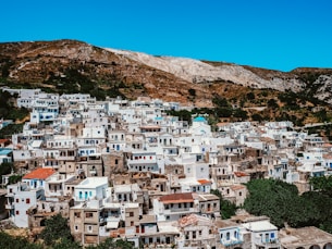 white and brown concrete houses near brown mountain under blue sky during daytime