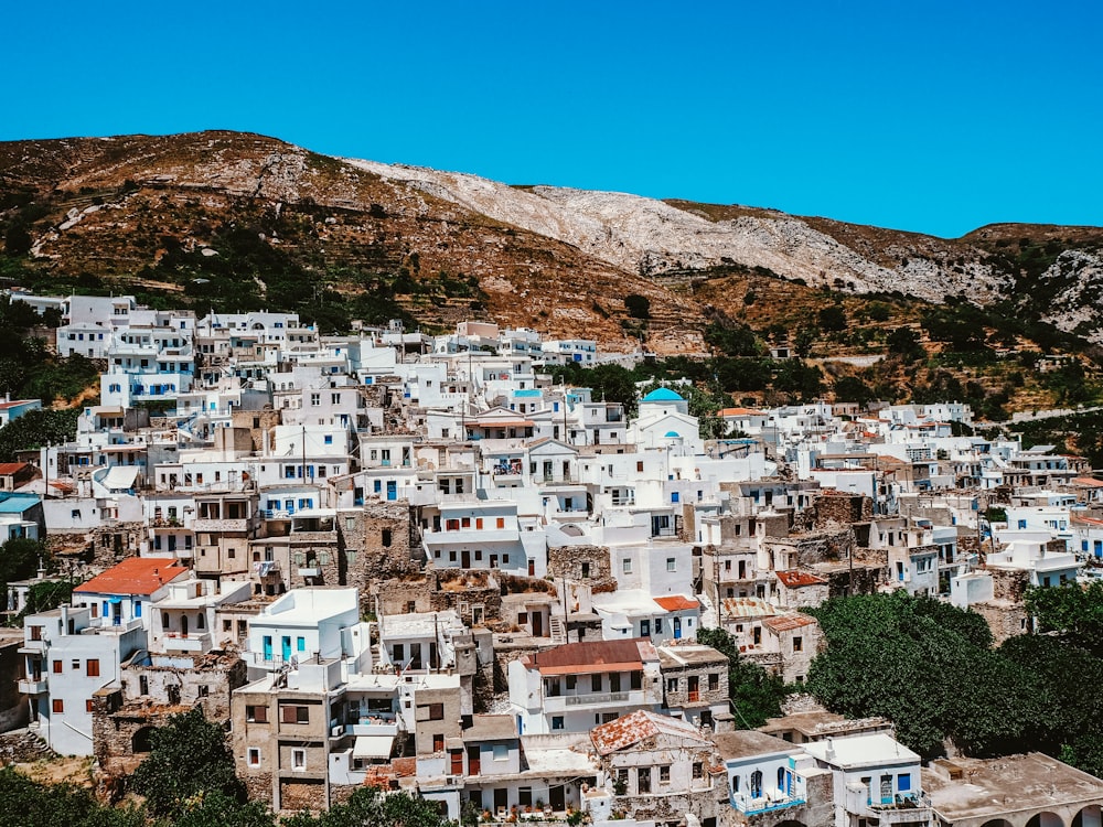 white and brown concrete houses near brown mountain under blue sky during daytime