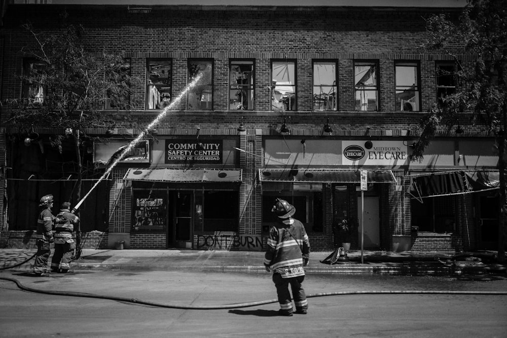 grayscale photo of man in black jacket and pants holding stick