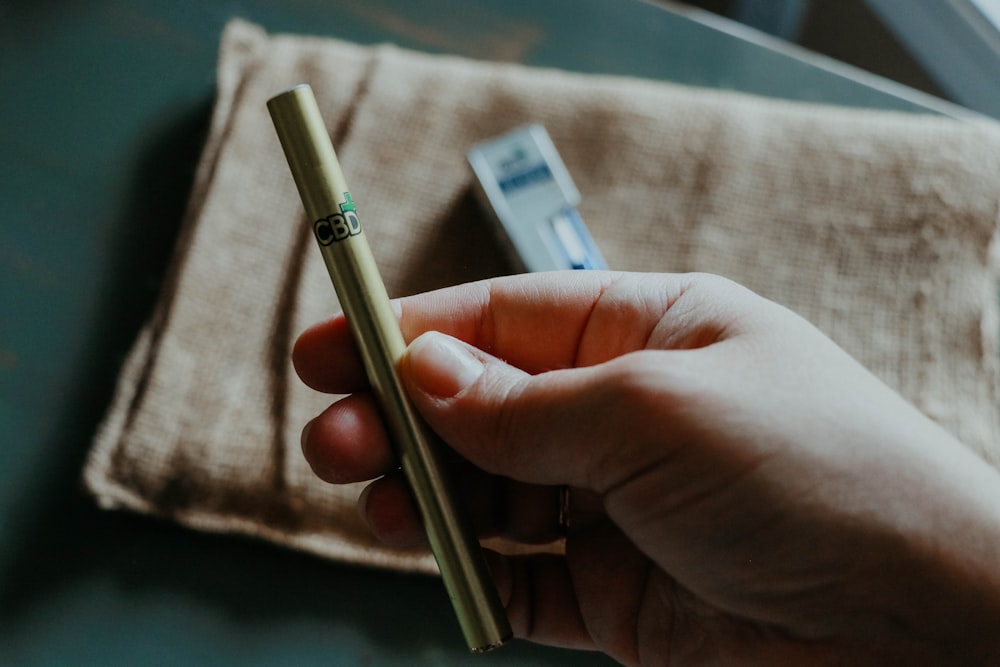 person holding silver and gold pen