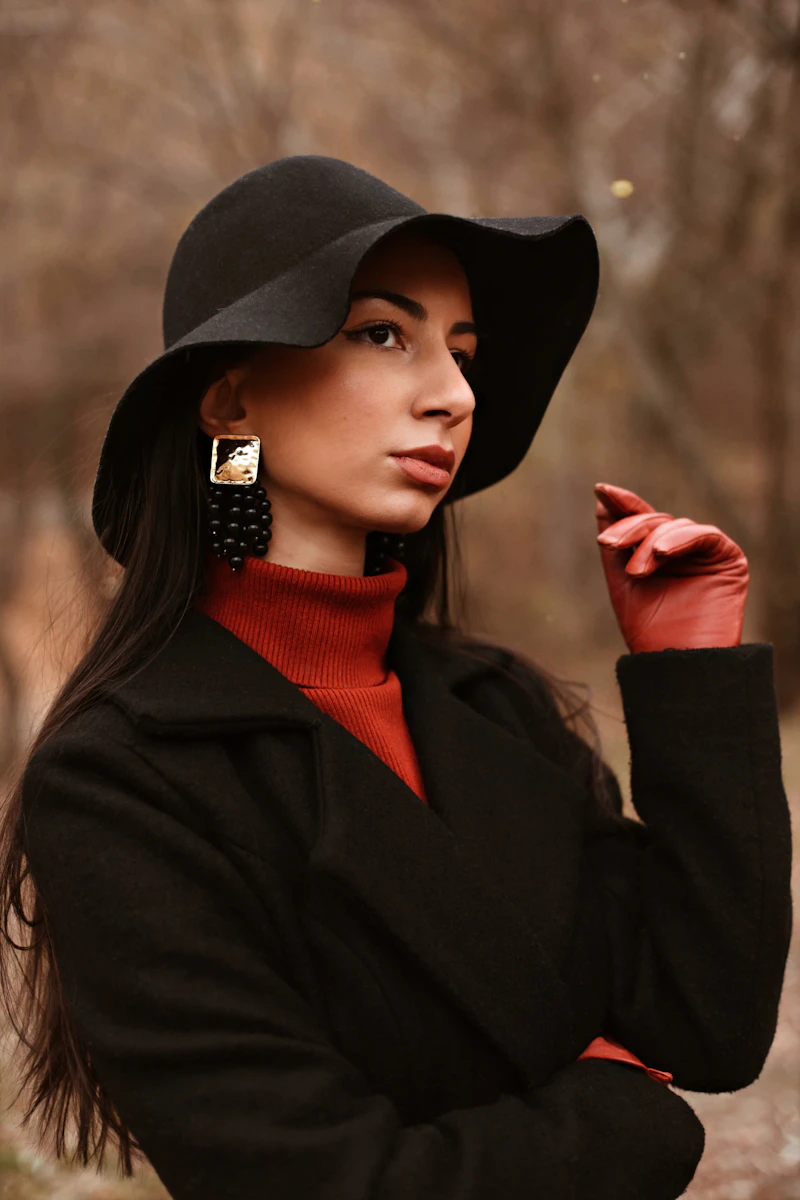 Portrait d'une femme en chapeau et manteau noirs, esthétique minimaliste.