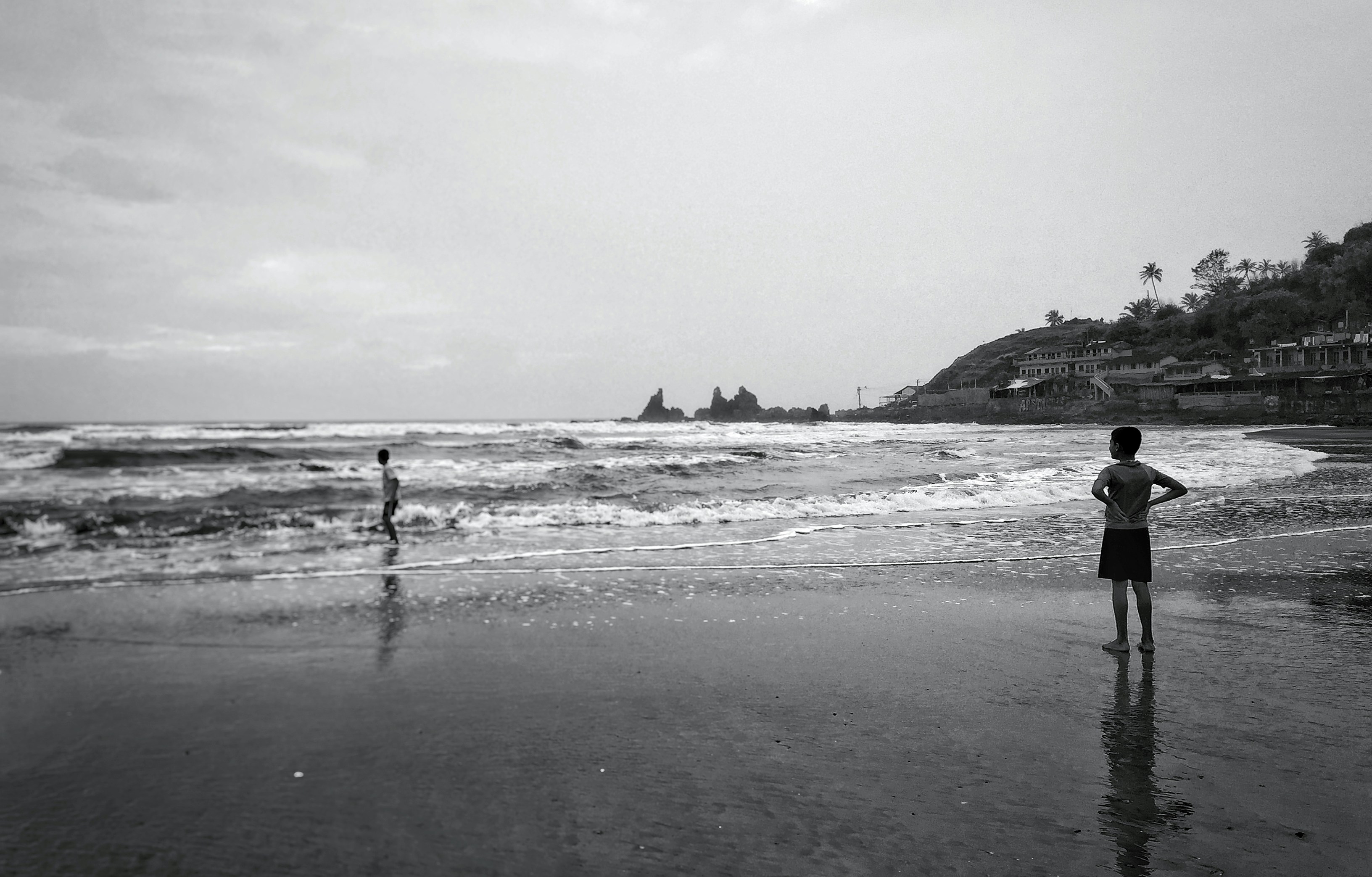 grayscale photo of person standing on beach