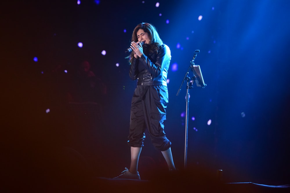 woman in black jacket singing on stage