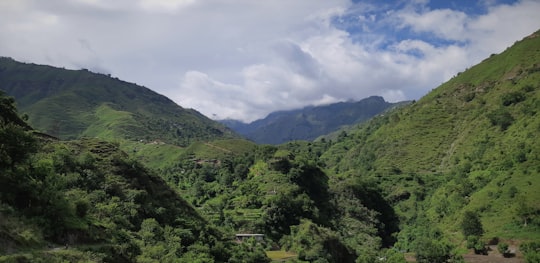 green mountains under white clouds during daytime in Chakrata India