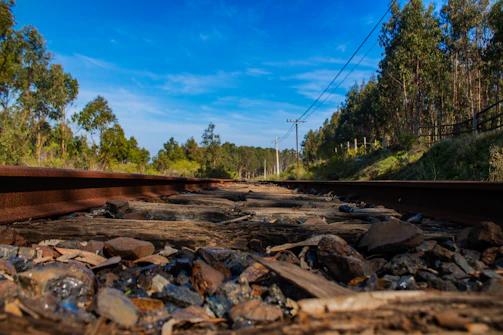 Close-up of skilled workers installing railway sleepers under a bright blue sky