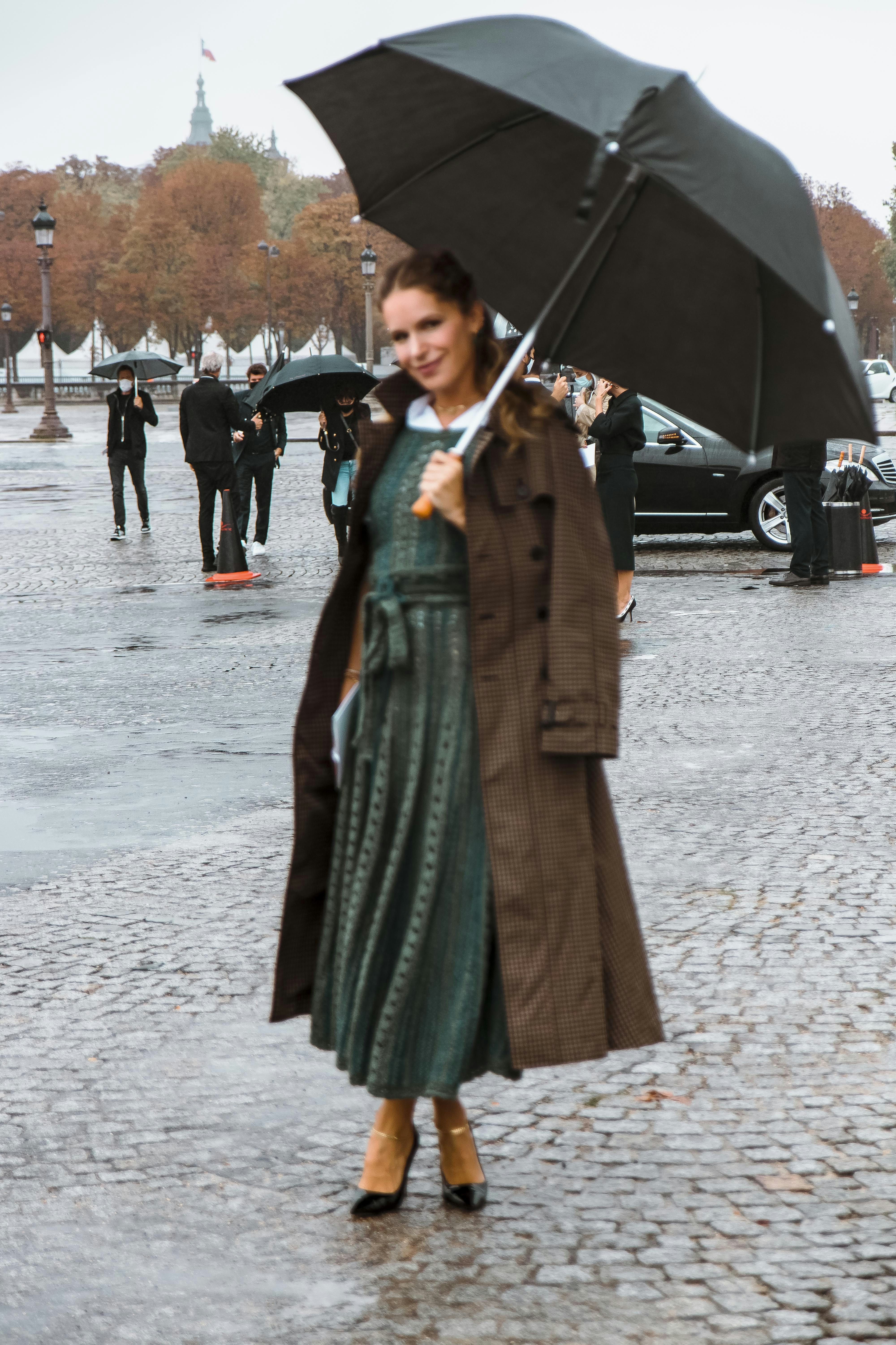 femme en manteau vert tenant un parapluie