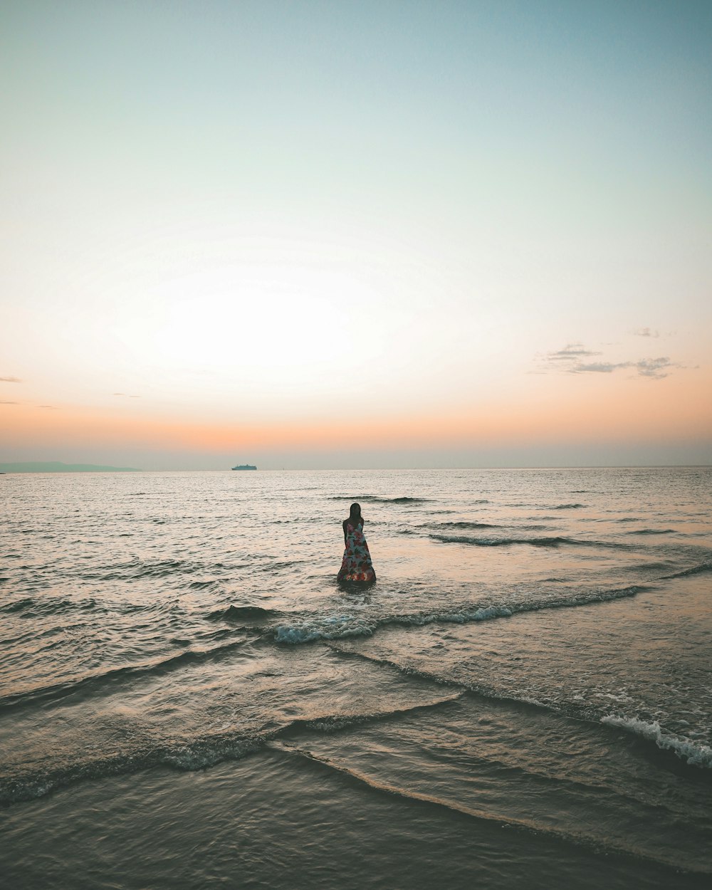 a person standing in the ocean at sunset