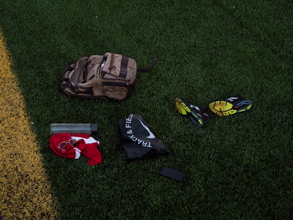 brown and black backpack on green grass