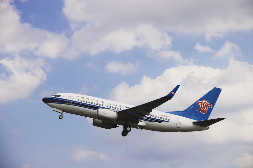 weiß-blaues Flugzeug tagsüber unter blauem Himmel