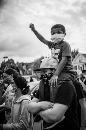 grayscale photo of man in t-shirt and shorts sitting on womans lap