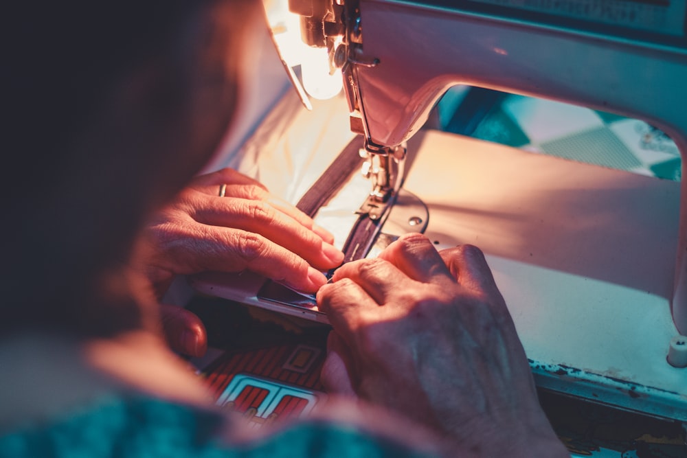 person playing sewing machine with white sewing machine