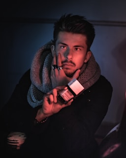 man in black sweater holding red and white ceramic mug
