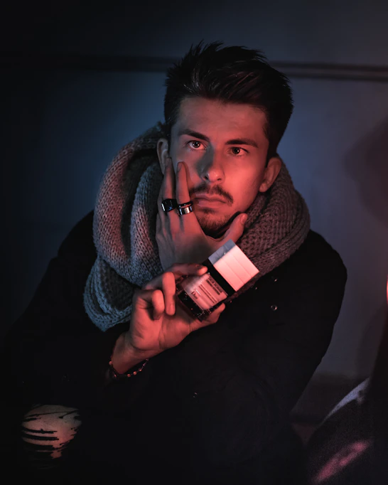 man in black sweater holding red and white ceramic mug