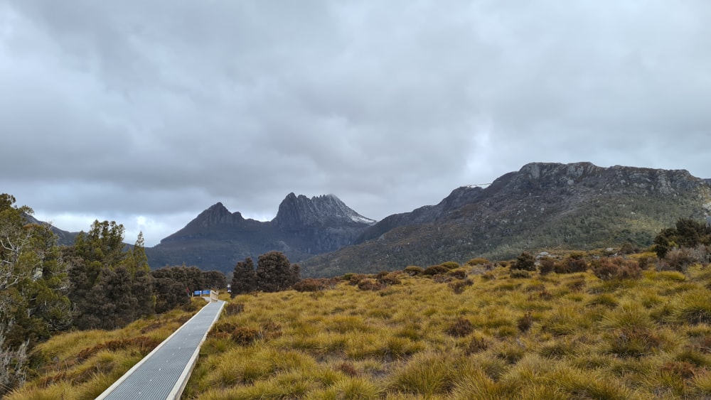 green grass field near mountain under white clouds during daytime