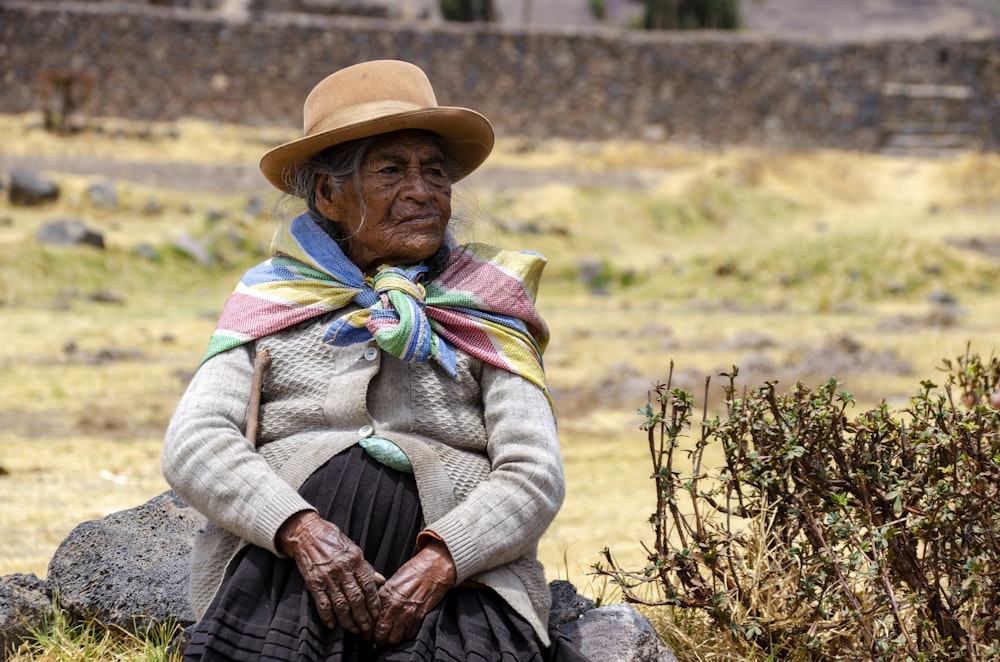 woman in brown hat and white sweater sitting on green grass field during daytime