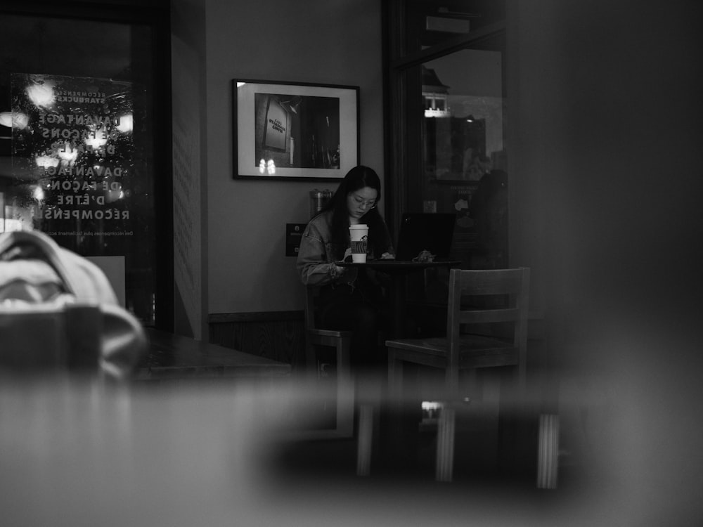 grayscale photo of man sitting on chair