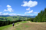 Travelers hiking along a lush green trail with distant hills on the horizon.