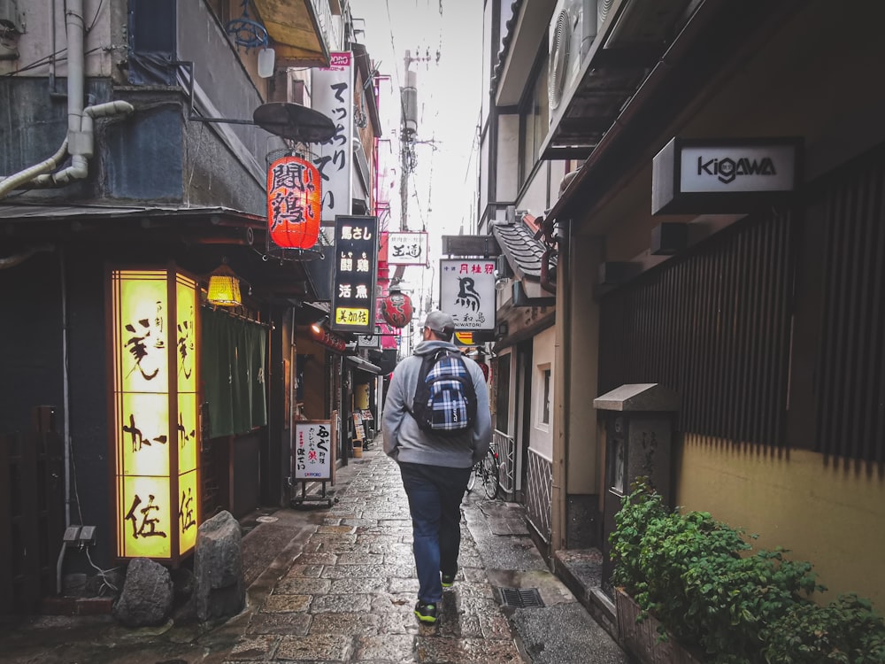 man in blue jacket and blue denim jeans walking on sidewalk during daytime