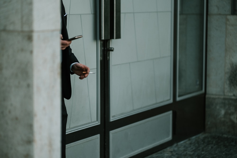 person holding black umbrella near white wooden framed glass window