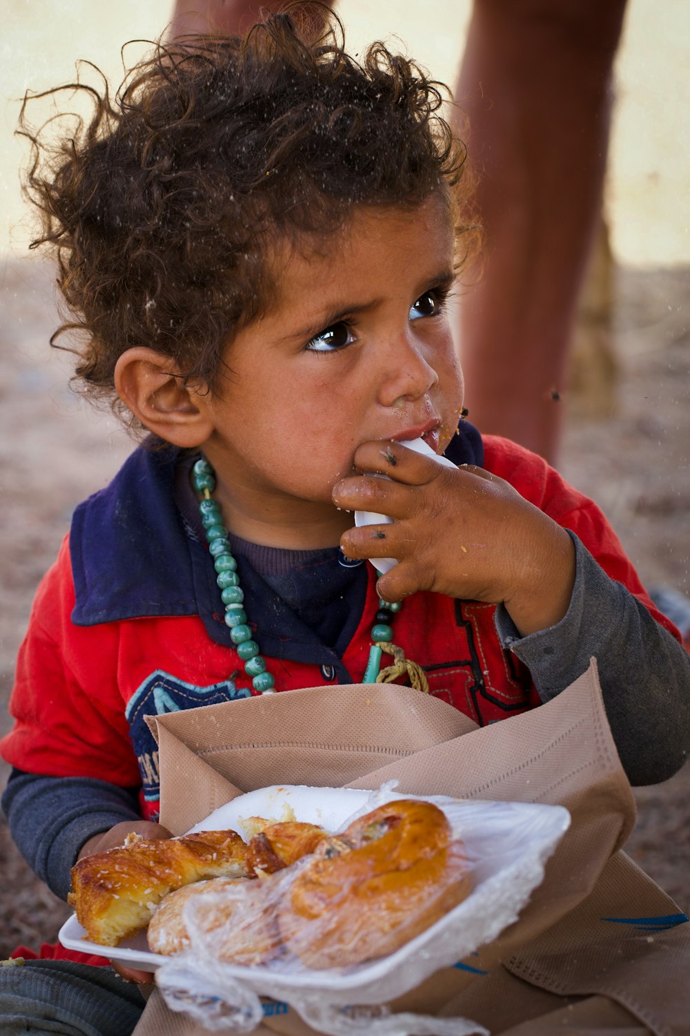 boy in red and blue jacket eating burger