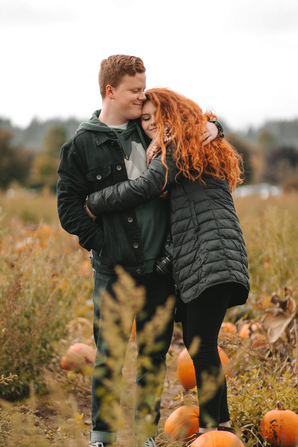 man in black leather jacket hugging woman in black leather jacket during daytime