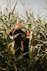 woman in black sleeveless dress sitting on corn field