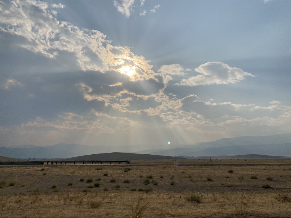 brown grass field under white clouds during daytime