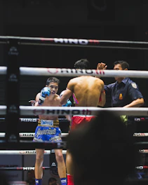 Close-up of a referee and trainee reviewing fight clips on a laptop screen.
