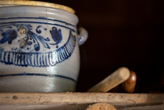 A charming vintage ceramic vase with delicate floral patterns sitting on a rustic shelf.