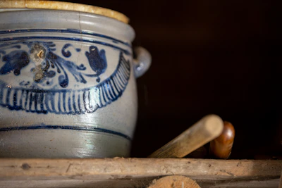 Close-up of artisan ceramic pots with delicate botanical patterns on a wooden shelf.
