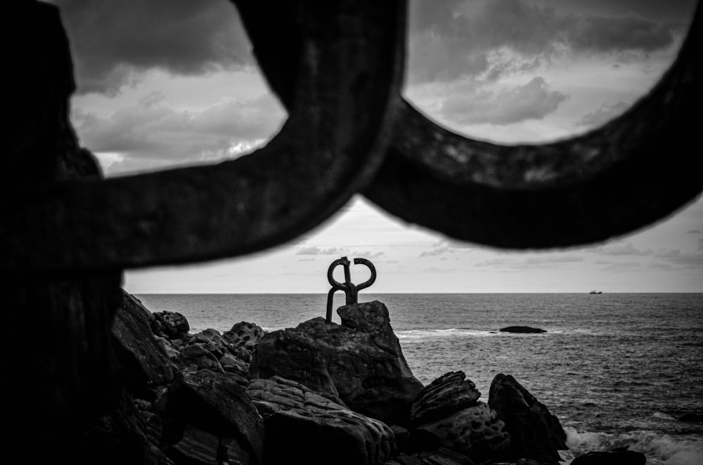 grayscale photo of rock formation near sea