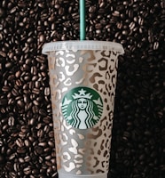 a starbucks cup sitting on top of a pile of coffee beans