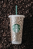 a starbucks cup sitting on top of a pile of coffee beans