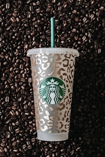 a starbucks cup sitting on top of a pile of coffee beans