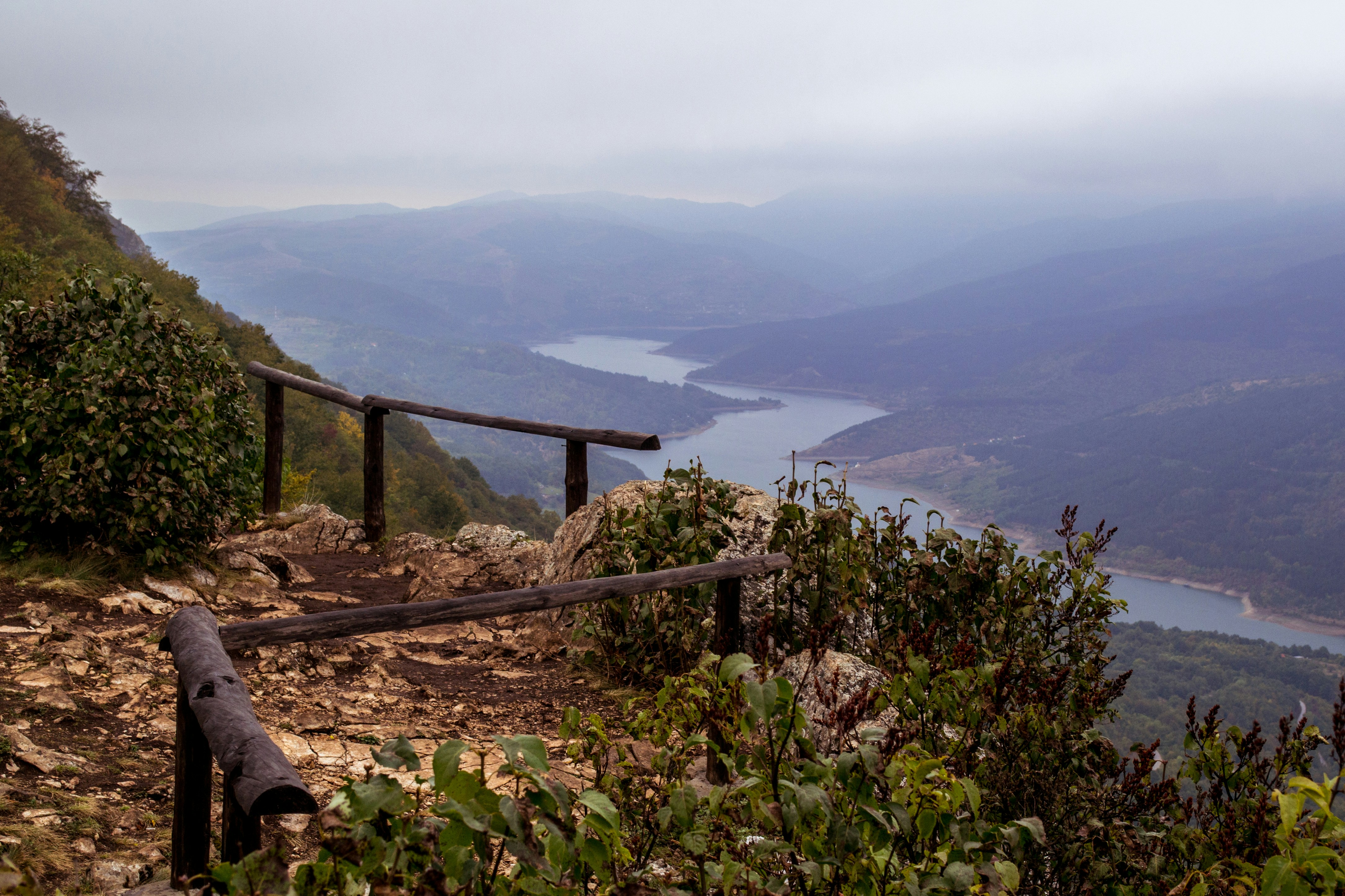 person sitting on brown wooden fence near green grass field during daytime