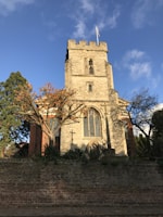 The historic stone facade of Fettercairn church framed by autumn leaves.