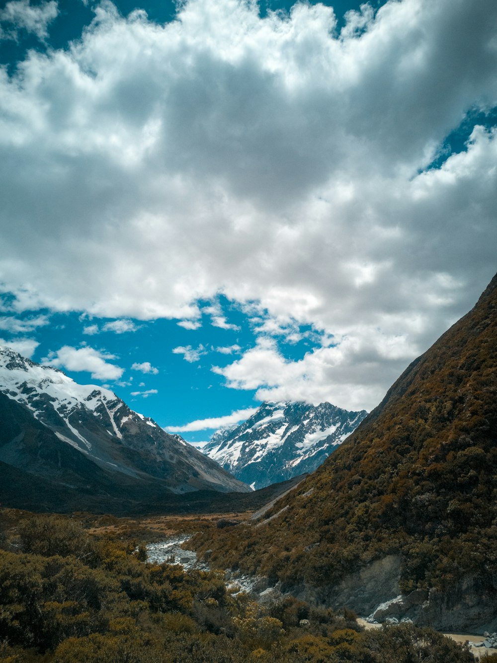 montanhas marrons e verdes sob nuvens brancas e céu azul durante o dia