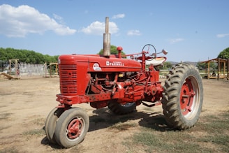 red tractor on green grass field under blue sky during daytime