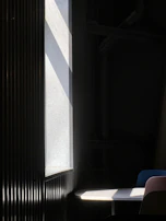 Golden sunlight casting sharp shadows on a minimalist, black-and-white construction office interior.