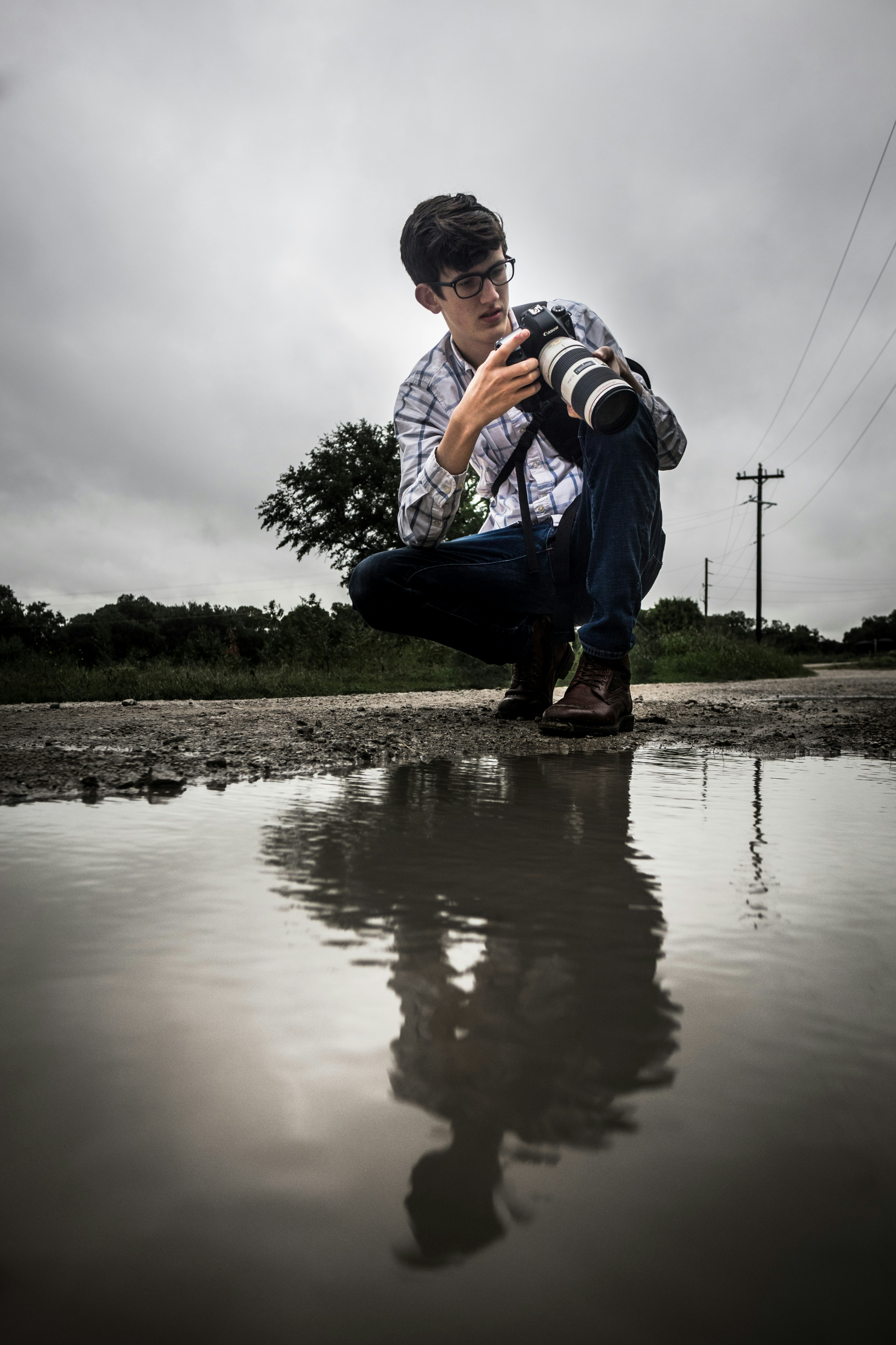 man in blue denim jeans and white shirt sitting on rock near river during daytime